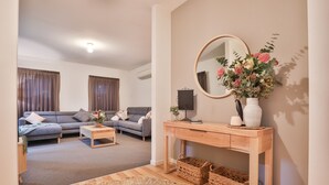 A modern living room with a grey sofa, a wooden coffee table, a console table with a mirror, and wicker baskets. - Modern 4 bedroom house with marina mooring, 2km from CBD (Mildura)