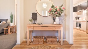A modern living room with a wooden console table, a round mirror, a vase with flowers, and wicker baskets. - Modern 4 bedroom house with marina mooring, 2km from CBD (Mildura)