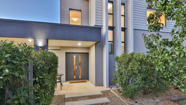 A modern building with a dark facade, a welcoming entrance with a door, and a gravel pathway leading to the entrance. - Modern 4 bedroom house with marina mooring, 2km from CBD (Mildura)
