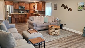 Un salon moderne avec un canapé gris, une table basse en bois et un tapis à motifs.