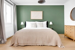 Un dormitorio con cama, dos mesitas de noche con lámparas, cómoda y un cuadro en la pared.