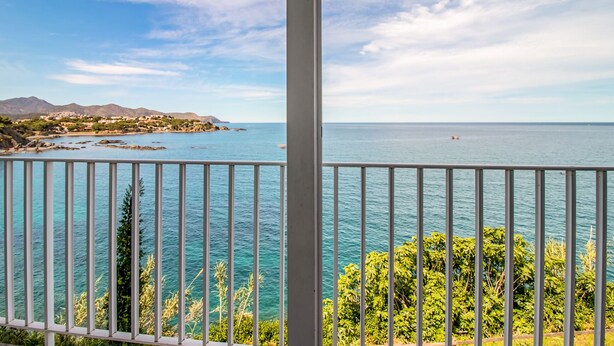 Un balcon donnant sur une ville côtière et la mer.