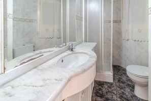 A bathroom with a white marble sink, a mirror, and a toilet.