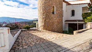 Una torre de piedra, un patio empedrado y un edificio con tejado de baldosas.