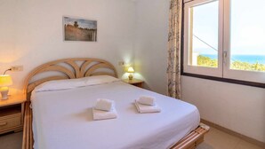 Un llit ben fet amb dues tovelloles doblegades, una làmpada de nit i un quadre a la paret.