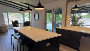 Una cucina moderna con un'isola grande, sgabelli da bar e luci a sospensione.
