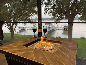Relax and unwind in this serene outdoor space, featuring a fire feature and stunning views of the calm body of water.