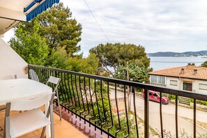A balcony with a table and chairs, overlooking a street with a red car and houses. - Carboneras 45 - Apartment with terrace (Llança)