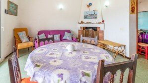 Een gezellige kamer met een ronde tafel, een paarse bank en houten stoelen.