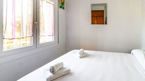 Een hotelkamer met twee bedden, een raam met gordijnen, een spiegel en een klein schilderij aan de muur.