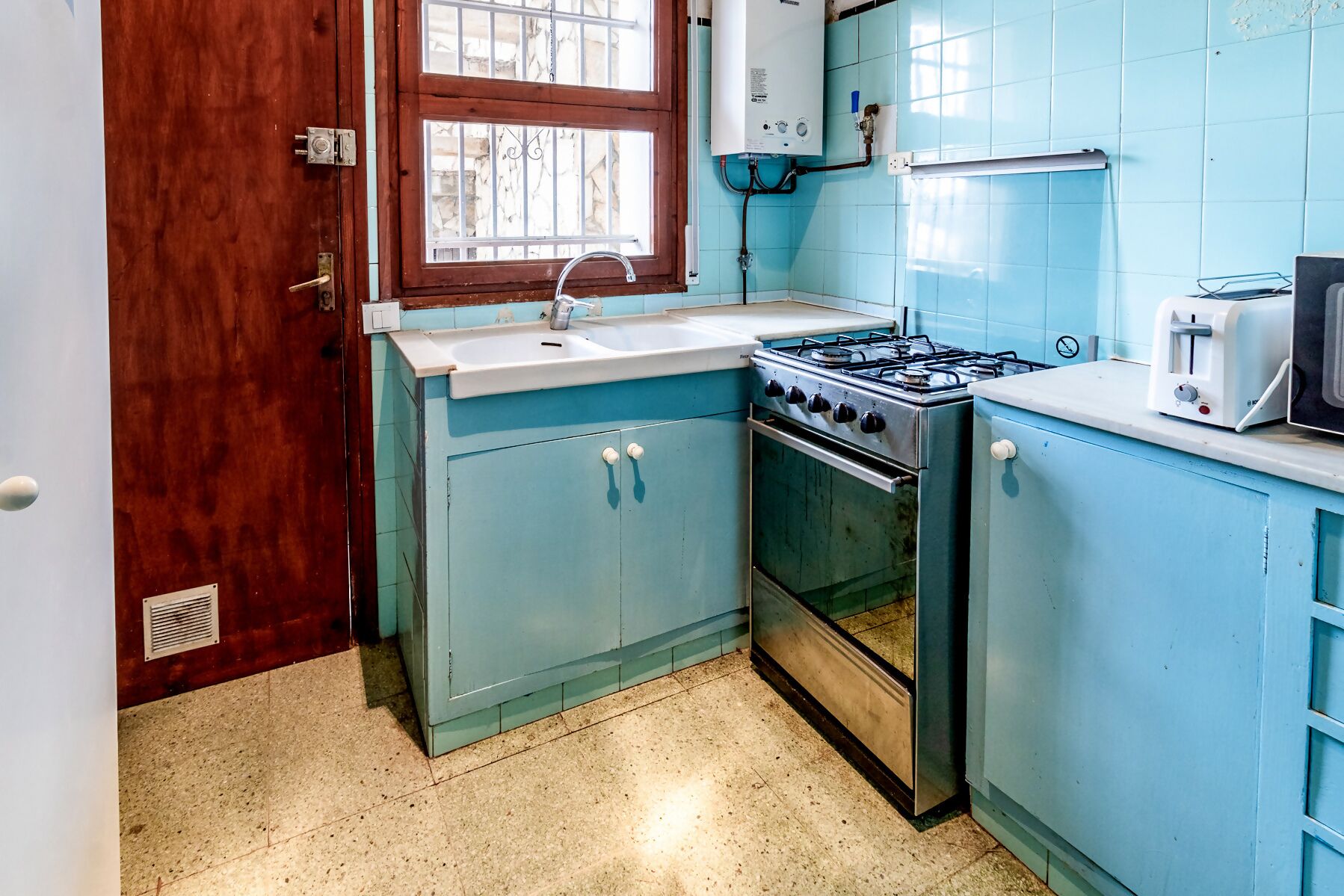 A kitchen with a stove, sink, and a window.