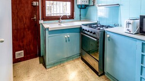 Een keuken met een fornuis, spoelbak en een raam.