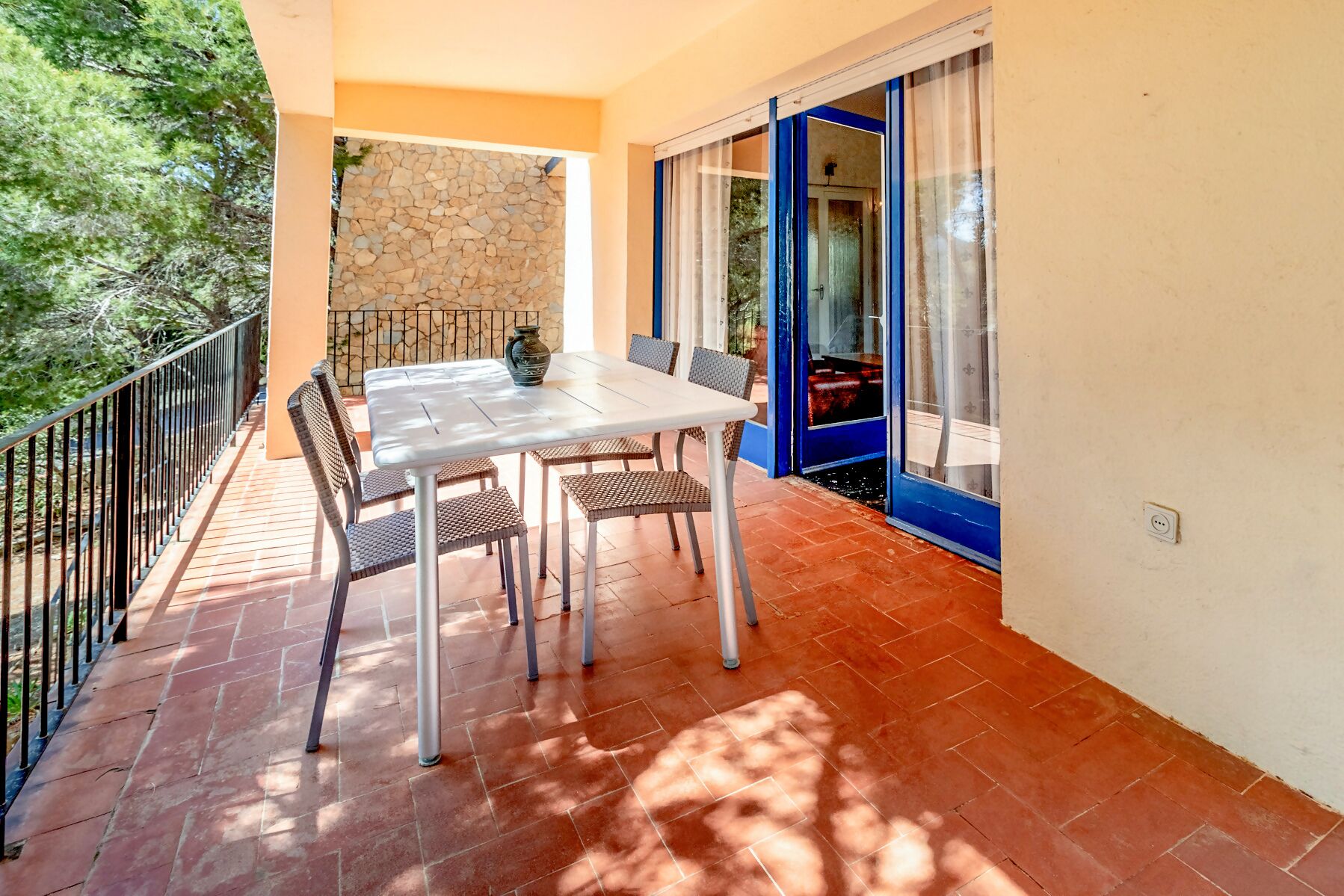 Un balcon avec une table et des chaises, un mur en pierre et une porte bleue.