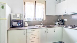 Une cuisine compacte équipée d’un four à micro-ondes, d’un grille-pain et d’une machine à café.