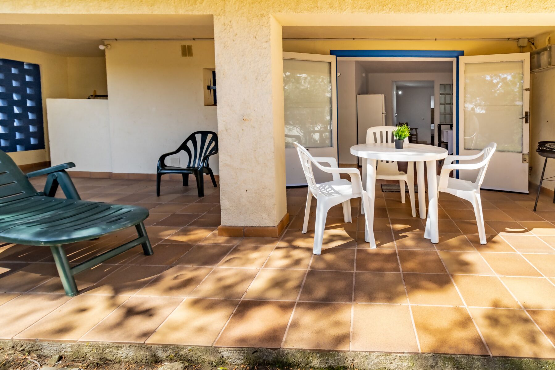 A patio area with a table and chairs, a green chair, and a white chair.