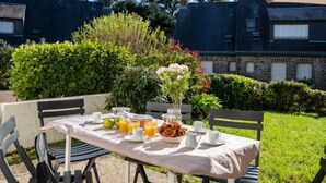 An outdoor dining area with a table set for breakfast, including fruits, pastries, and beverages. - La Sauvagère by Interhome (Carnac)