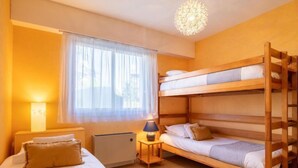 A room with bunk beds, a bedside table with a lamp, a radiator, and a window with sheer curtains. - La Sauvagère by Interhome (Carnac)