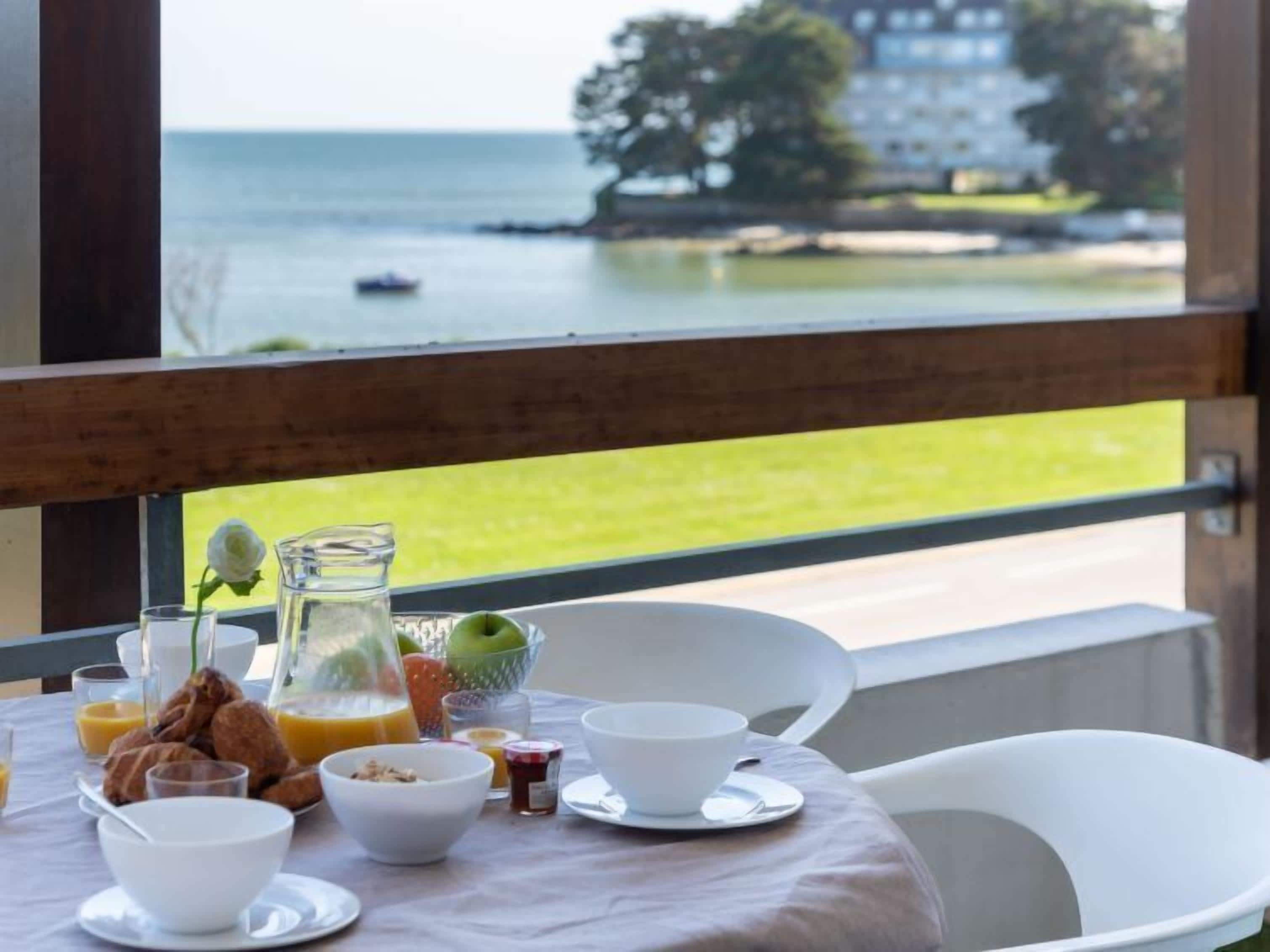 Une table de petit-déjeuner avec vue sur la mer et un bâtiment situé de l’autre côté.