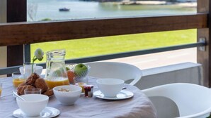 A breakfast table with a view of the sea and a building across the water. - Apartment MEN DU by Interhome (Carnac)