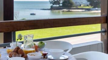 Une table de petit-déjeuner avec vue sur la mer et un bâtiment situé de l’autre côté.