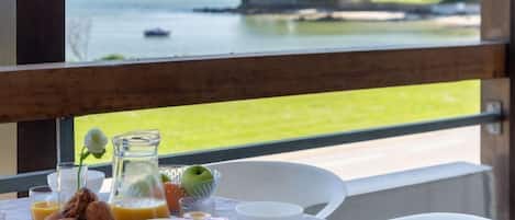 Ett frukostbord med utsikt över havet och en byggnad på andra sidan vattnet.