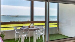 A balcony with a table set for dining, overlooking a beach and the sea. - Apartment MEN DU by Interhome (Carnac)