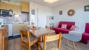 A compact living space with a dining area, kitchenette, and a red sofa. - Apartment MEN DU by Interhome (Carnac)