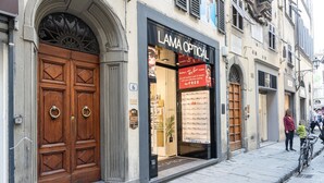 A storefront with a large wooden double door and a sign that reads 'LAMA OPTICAL.'