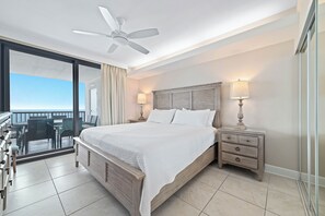 A hotel room with a bed, nightstands, a ceiling fan, a balcony with a table and chairs, and a view of the ocean. - Summerhouse #1205A- DIRECT BEACH FRONT, RECENTLY RENOVATED, GREAT LOCATION! (Orange Beach)