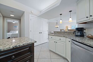 A kitchen with granite countertops, white cabinets, a dishwasher, and pendant lighting. - Summerhouse #1205A- DIRECT BEACH FRONT, RECENTLY RENOVATED, GREAT LOCATION! (Orange Beach)