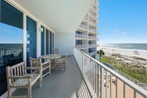 Ein Balkon mit Blick auf den Strand, Holzmöbel und einem Geländer.