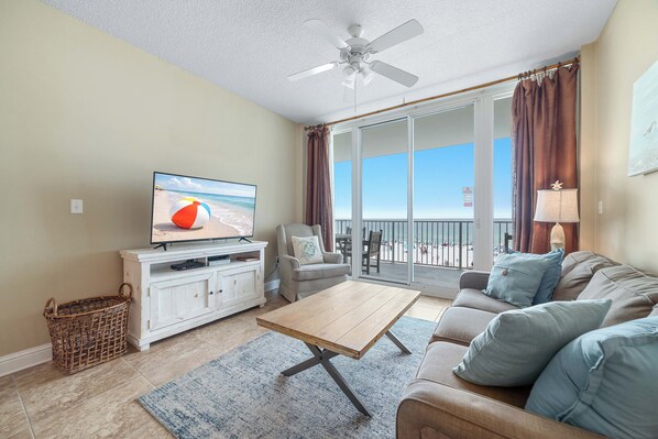 Ein Wohnzimmer mit Fernseher, Sofa, Couchtisch und einem Balkon mit Blick.