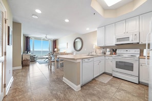 A modern kitchen with white cabinets, a large island, and a built-in oven.