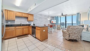 Una cocina con armarios de madera, lavavajillas y un comedor con una silla y mesa.