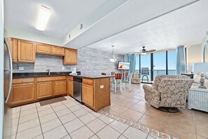 A kitchen with wooden cabinets, a dishwasher, and a dining area with a chair and table.