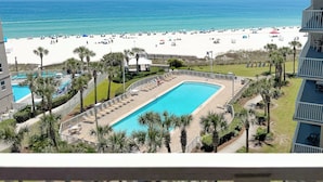 Un resort con piscina, vistas a la playa y palmeras.