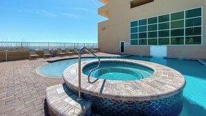 Une piscine avec un jacuzzi, des chaises longues et une vue sur l’océan.