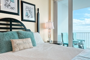 Relax in this inviting room with a large bed, a balcony offering a view, and a side table with a lamp.