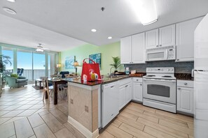 Enjoy meals in the adjacent dining area with a view of the outdoors, adjacent to a well-equipped kitchen with a large island and appliances.