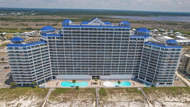Ein großes, mehrstöckiges Hotel mit einem zentral gelegenen Swimmingpool und Blick auf die umliegende Landschaft.