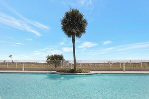 Relax by the pool surrounded by lush greenery and a single palm tree.