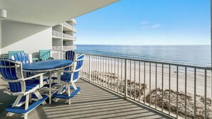 Ein Balkon mit Tisch und Stühlen mit Blick auf einen Strand.