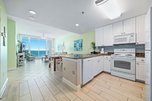 A modern kitchen with white cabinets, a dishwasher, a microwave, and an oven.