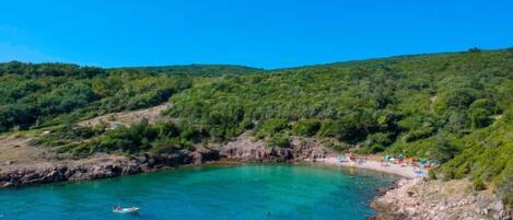 Un paysage côtier caractérisé par des eaux turquoise limpides, des rivages rocheux et des collines verdoyantes et luxuriantes.