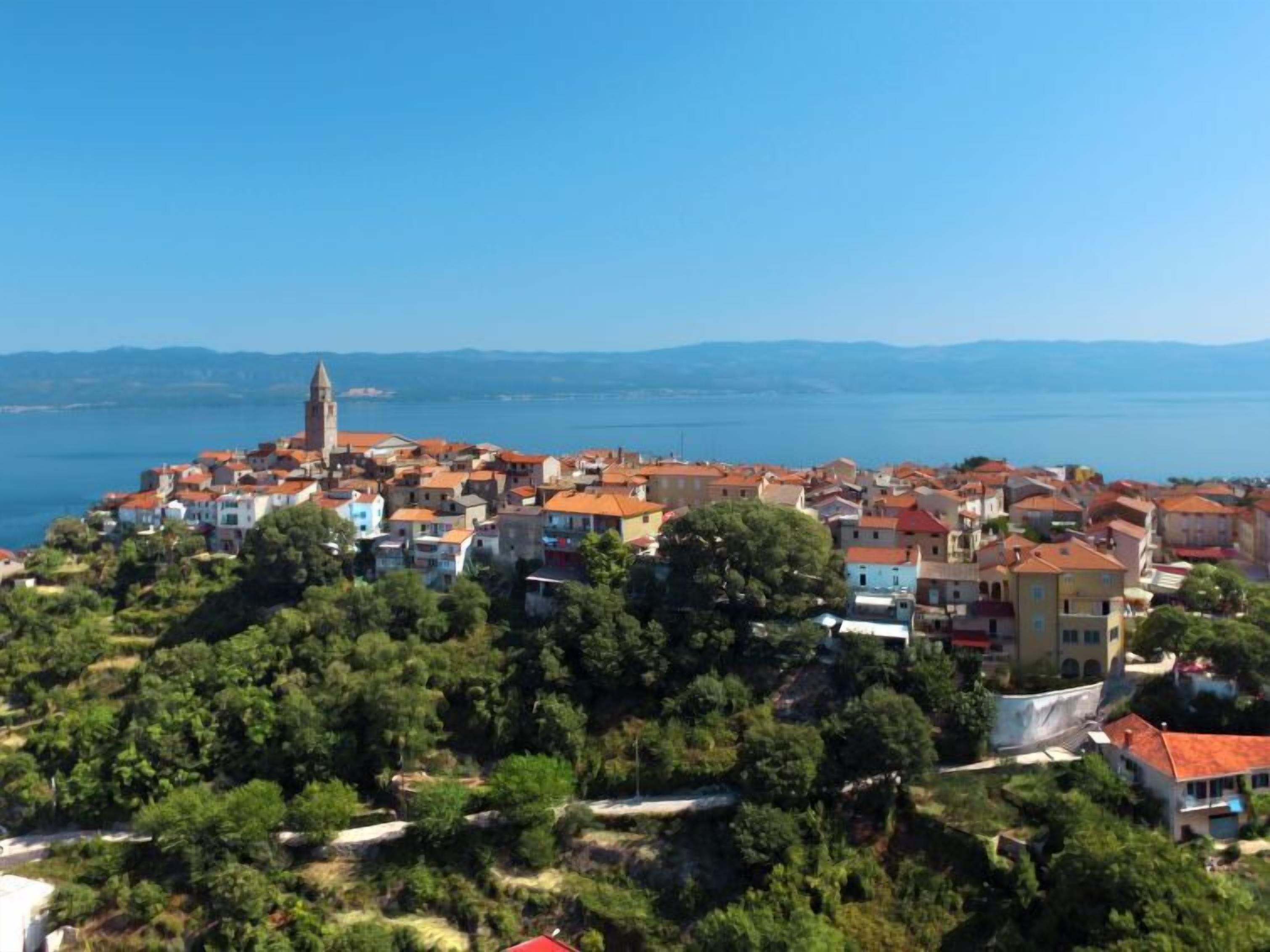 Un pueblo costero con una imponente torre de iglesia, viviendas densas y una vista despejada del mar.