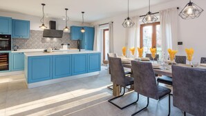 Una cocina moderna con armarios azules, una isla central e iluminación colgante.