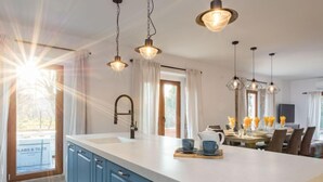 Una cocina moderna con una isla grande, iluminación colgante y vistas al exterior.