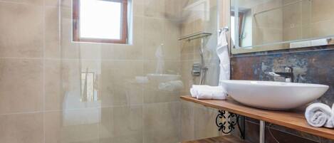 Une salle de bain moderne avec une douche à parois de verre, un grand lavabo sur pied et un meuble-lavabo en bois.
