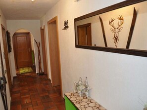 A hallway with a wooden door, a mirror, and a decorative wall piece. - Nice apartment for 8 guests with WIFI, TV, balcony and pets allowed (Kappl)