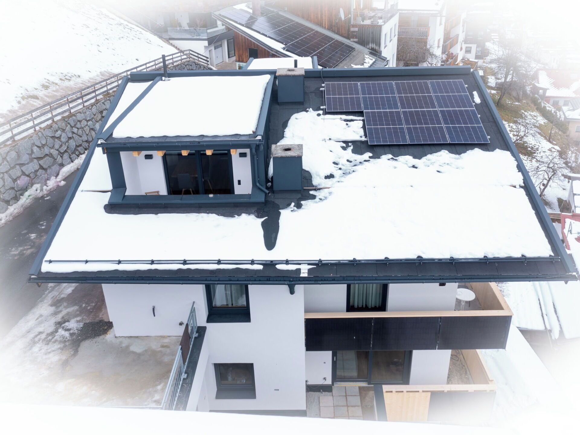 Een modern gebouw met een plat dak, zonnepanelen en een stenen muur.
